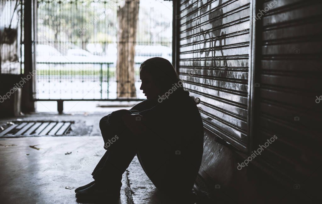 homeless woman sitting on street side