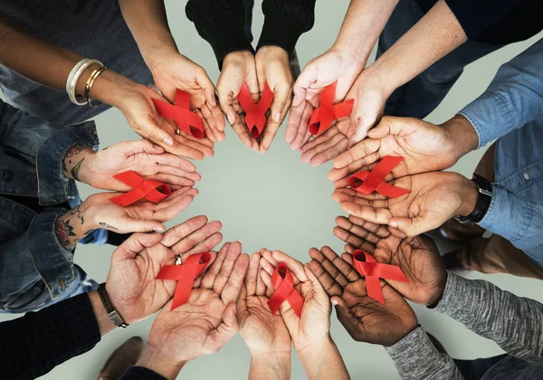 Människor händer som håller röda band — Stockfoto