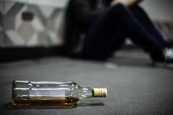 Muž sedí na podlaze láhev alkoholu — Stock fotografie