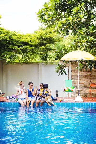 Разнообразные женщины сидят у бассейна — стоковое фото