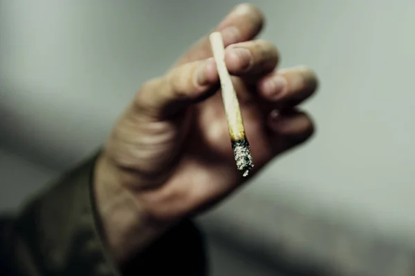 Pria tunawisma memegang rokok — Stok Foto