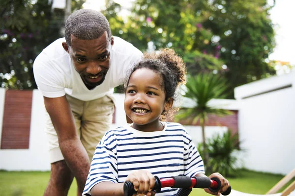 father teaching daughter ride bike