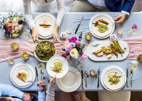 Personas sentadas a la mesa con comida — Foto de Stock