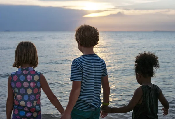 Діти стоять на пляжі і тримаються за руки — стокове фото