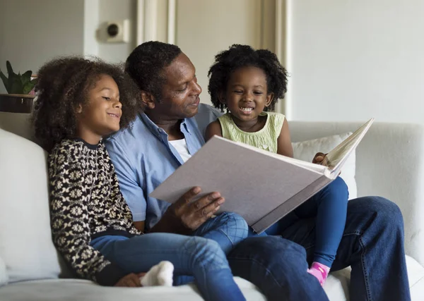 Отец читает книгу с дочерьми — стоковое фото