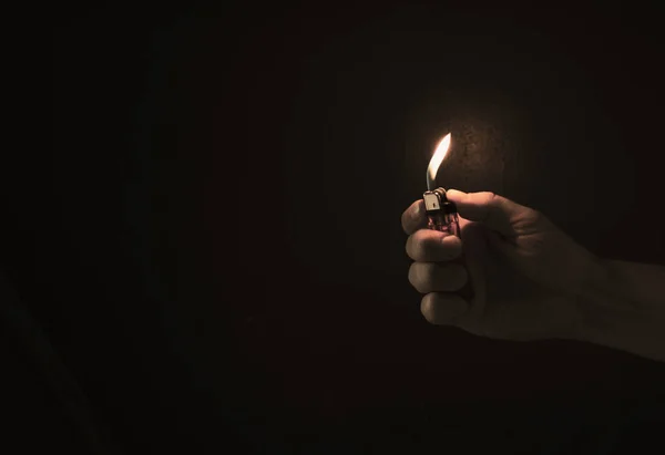 Рука держит зажигалку в темноте — стоковое фото