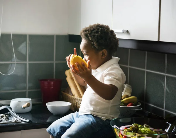 Černý chlapec s pomerančem v kuchyni — Stock fotografie