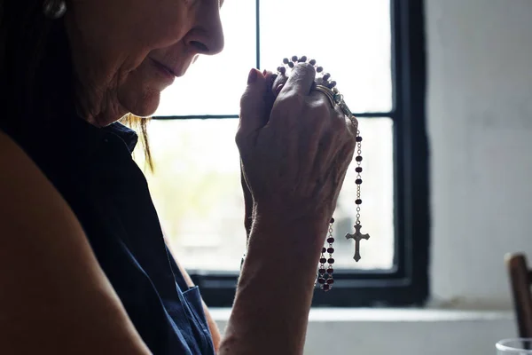 Alte Frau betet mit Kreuz — Stockfoto
