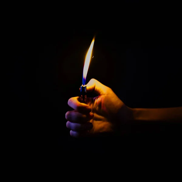 Hand holding lit lighter in the dark — Stock Photo, Image