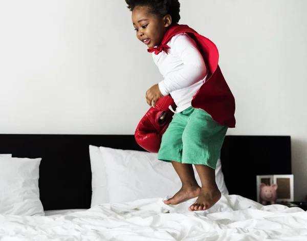 Niño saltando en la cama con bata — Foto de Stock