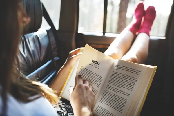 Woman reading book in a car — Stock Photo, Image