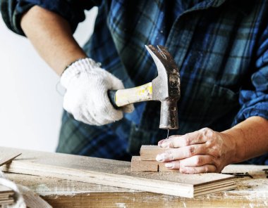 Özgün bir tahtaya çivi iterek çekiç kullanarak kadın marangoz photoset
