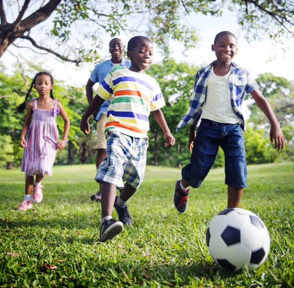 元の公園でサッカーで遊んでアフリカの家族写真植字 — ストック写真