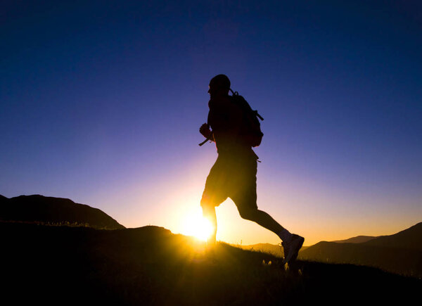 Man's silhouette running in a sunset with mountain range as a background, original photoset