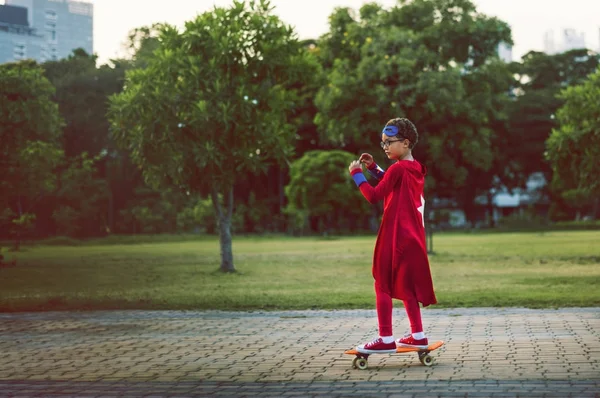 Superhéroe niño en un monopatín — Foto de Stock