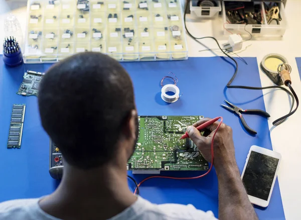 Technician using multimeter with computer electronics parts, original photoset