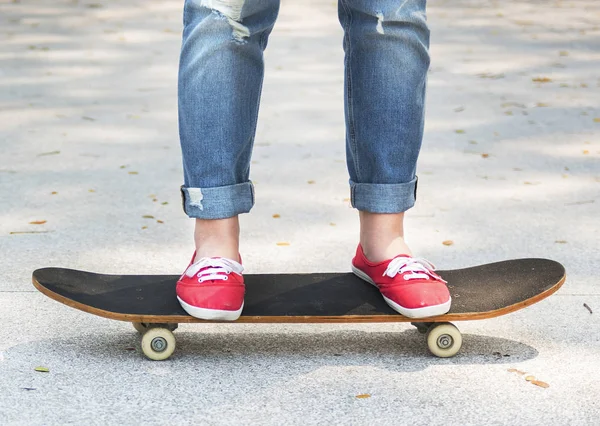 Pernas de menina em um skate — Fotografia de Stock