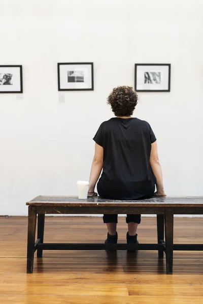 女性の座っているベンチで写真展 オリジナルのフレームを見ての背面写真植字 — ストック写真