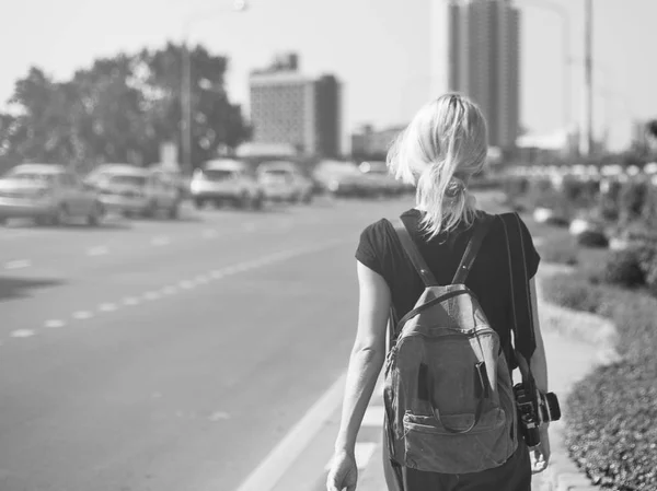 Kvinna med ryggsäck promenader längs vägen — Stockfoto