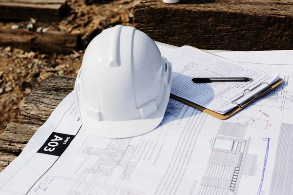 Local de construção com planta e capacete — Fotografia de Stock