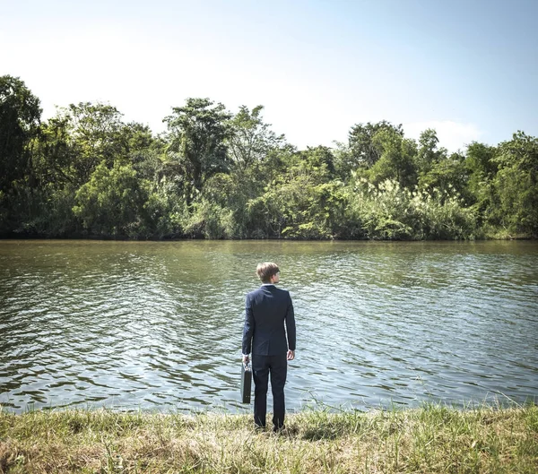 Бизнесмен, стоящий у реки — стоковое фото