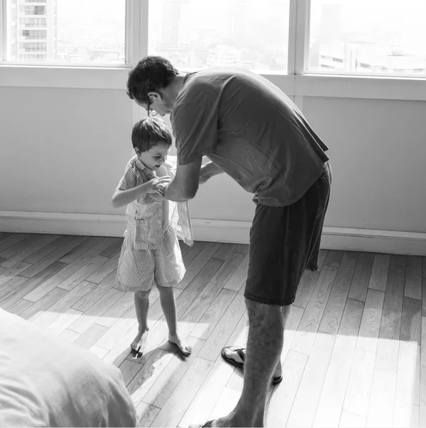 Отец помогает сыну одеться — стоковое фото