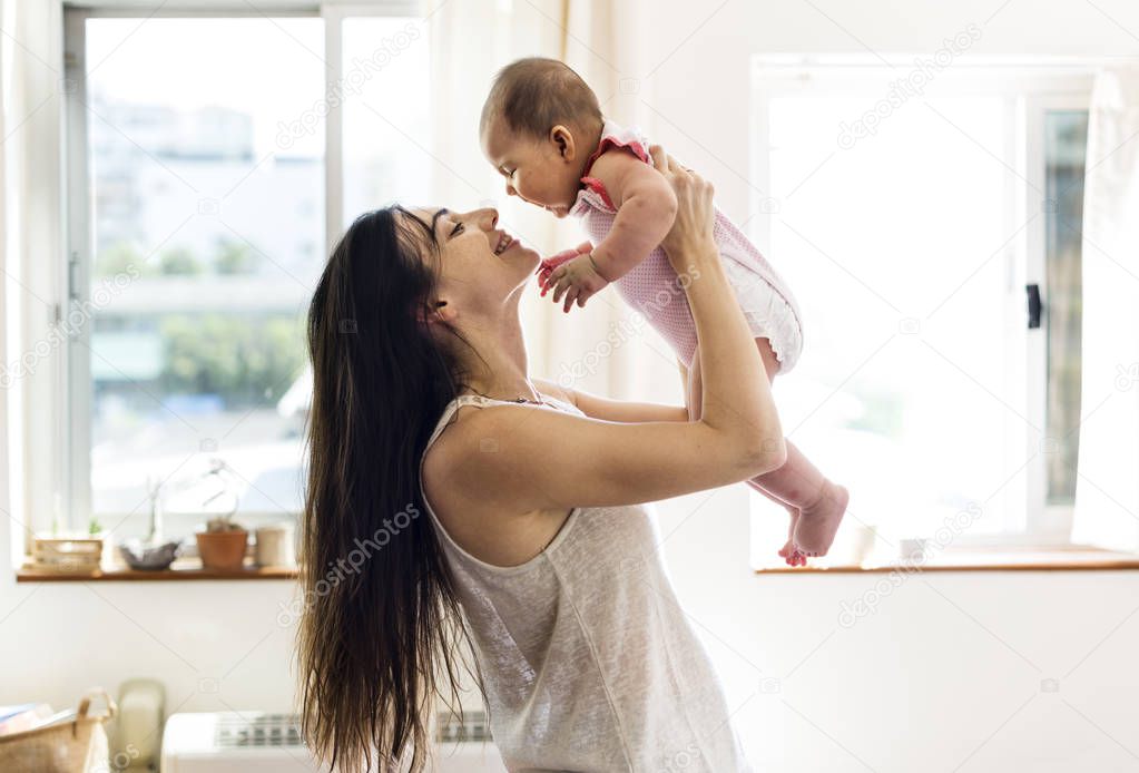 mother holding newborn baby on rised up hands in front of window, original photoset 