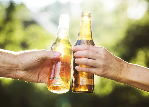 Крупним планом руки стискають пляшку пива разом — стокове фото