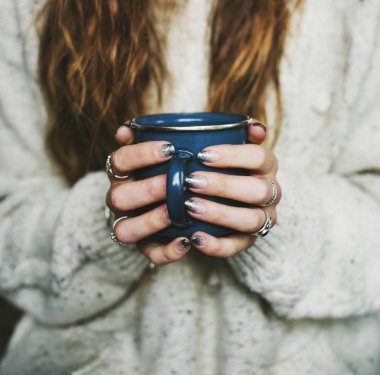 Kahve fincanını tutan ellerin yakın çekimi.