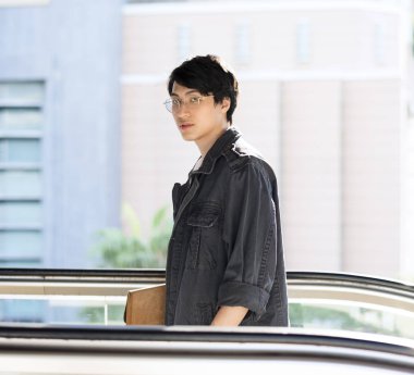 Yakışıklı Asya'ya ait adam yürüyen merdiven üzerinde