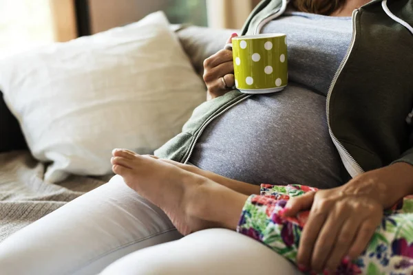 Gravid Kvinne Med Kopp Sittende Sofaen Med Liten Datter – stockfoto
