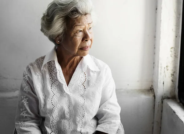 Ηλικιωμένη γυναίκα της Ασίας αναζητούν έξω από το παράθυρο — Φωτογραφία Αρχείου