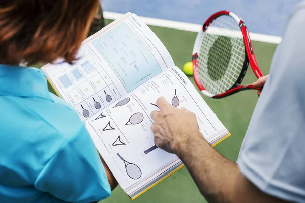 Chica y entrenador leyendo libro de tenis —  Fotos de Stock