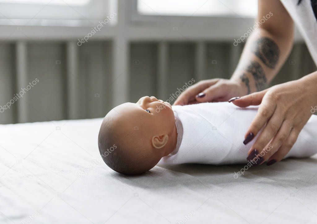 woman learning to swaddle newborn on doll-dummy in a class, original photoset