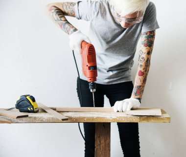 bir tahtaya bir matkap kullanarak marangoz kadın