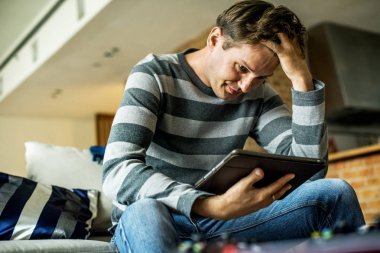 Dijital tablet için arıyorum ve oturma odasında kanepede oturan beyaz adam