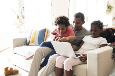 Kanepede oturan ve laptop için arıyorsunuz iki çocuk ile Afrika baba