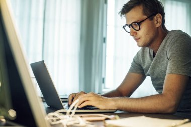 Adam evde dizüstü bilgisayarla çalışıyor.