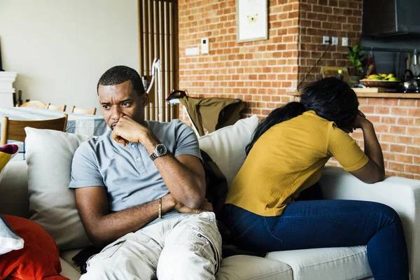 african couple sitting on couch after quarrels