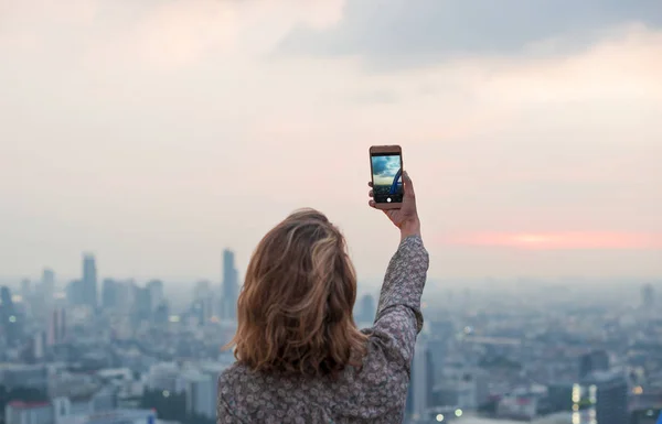女性が携帯電話で夕日の写真を撮る — ストック写真