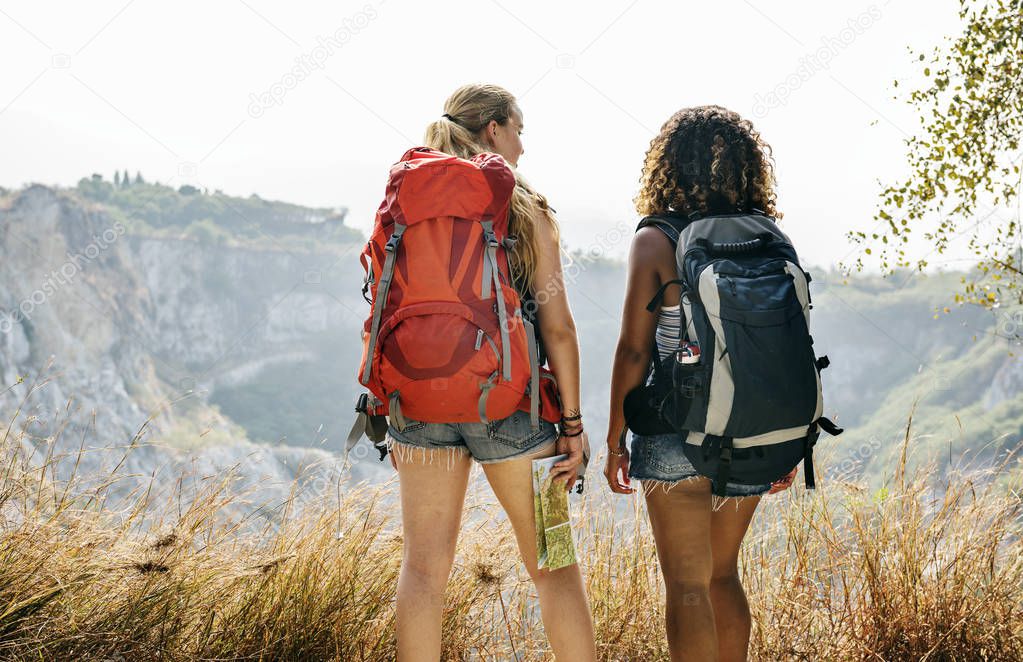 Back view on two women with Backpacks looking to mountains