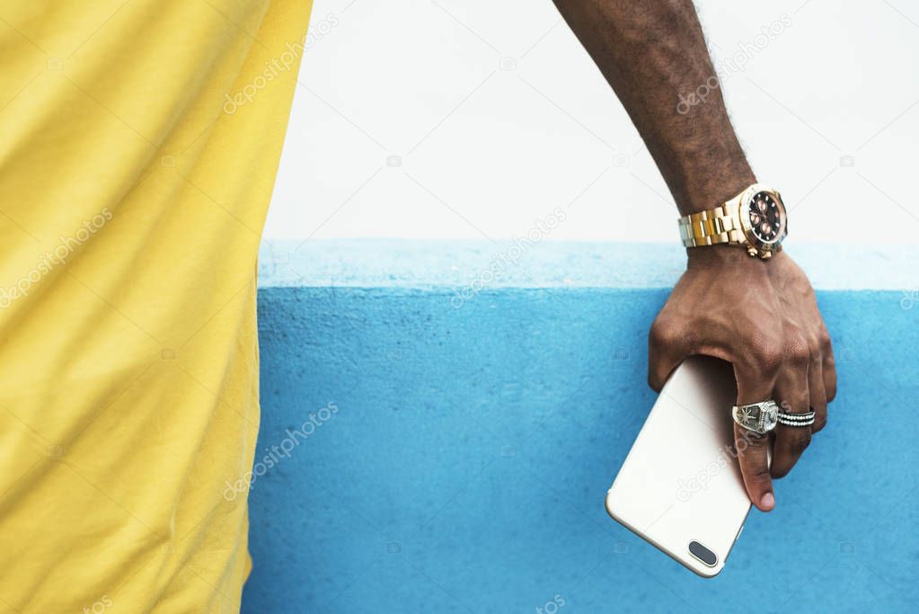 hand of african man with rings and golden watch holding a smart phone