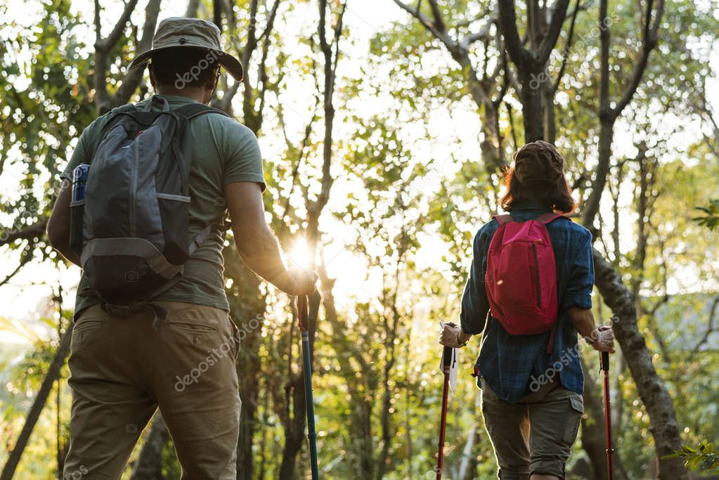 Couple with backpacks hiking in jungle together