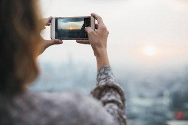 Kadın alarak fotoğraf günbatımı üstünde hareket eden telefon
