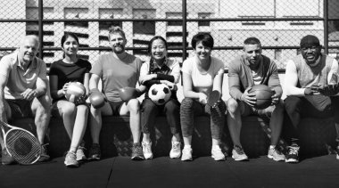 Siyah-beyaz çeşitli spor aletleri ile birlikte oturan çok etnik atletler grubu