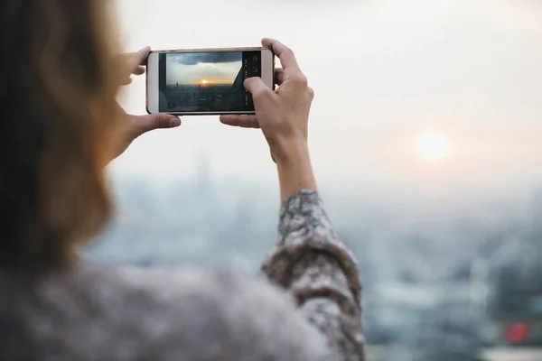 女性は携帯電話で夕焼けの写真を撮影 — ストック写真