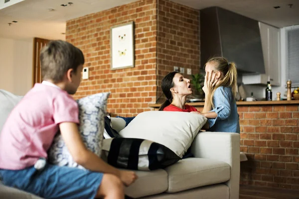 Mother consoling daughter and son sitting on the couch