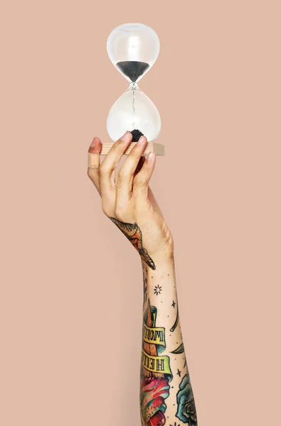 砂時計を保持しているベージュの背景に入れ墨をした人間の手 — ストック写真