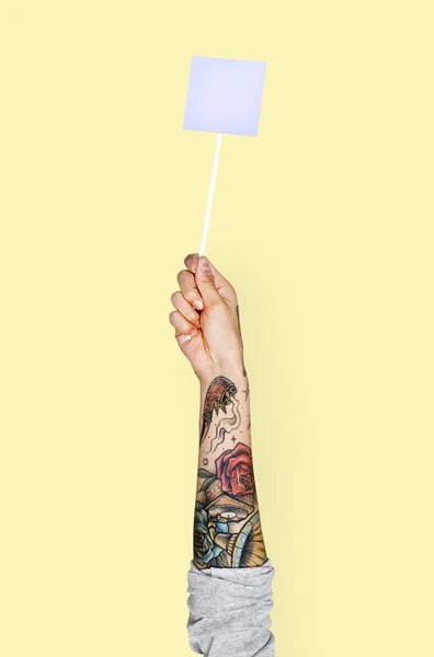 Людська Рука Татуюваннями Жовтому Тлі Тримає Маленький Папір Пустий Паличці — стокове фото