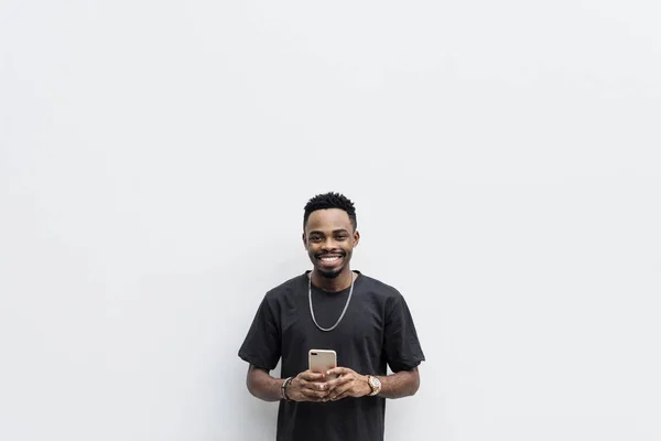 Afrikai Férfi Fekete Póló Fehér Háttér Mobiltelefonnal — Stock Fotó